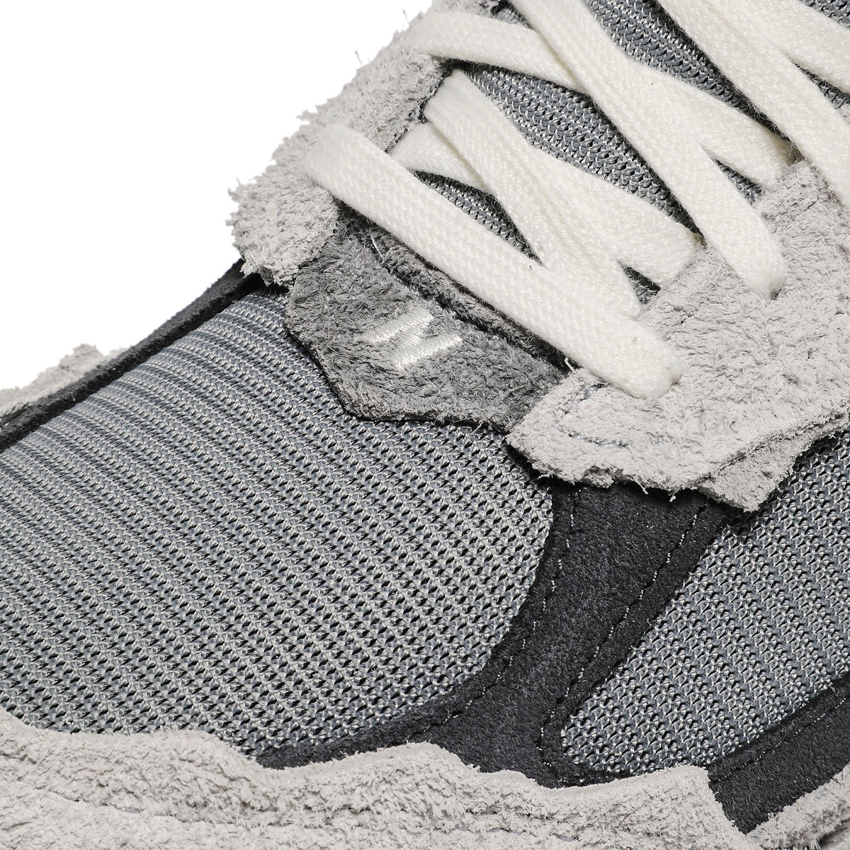 Gros plan du daim gris aux bords effilochés de la New Balance 2002R Protection Pack Rain Cloud, lacets crème et mesh gris