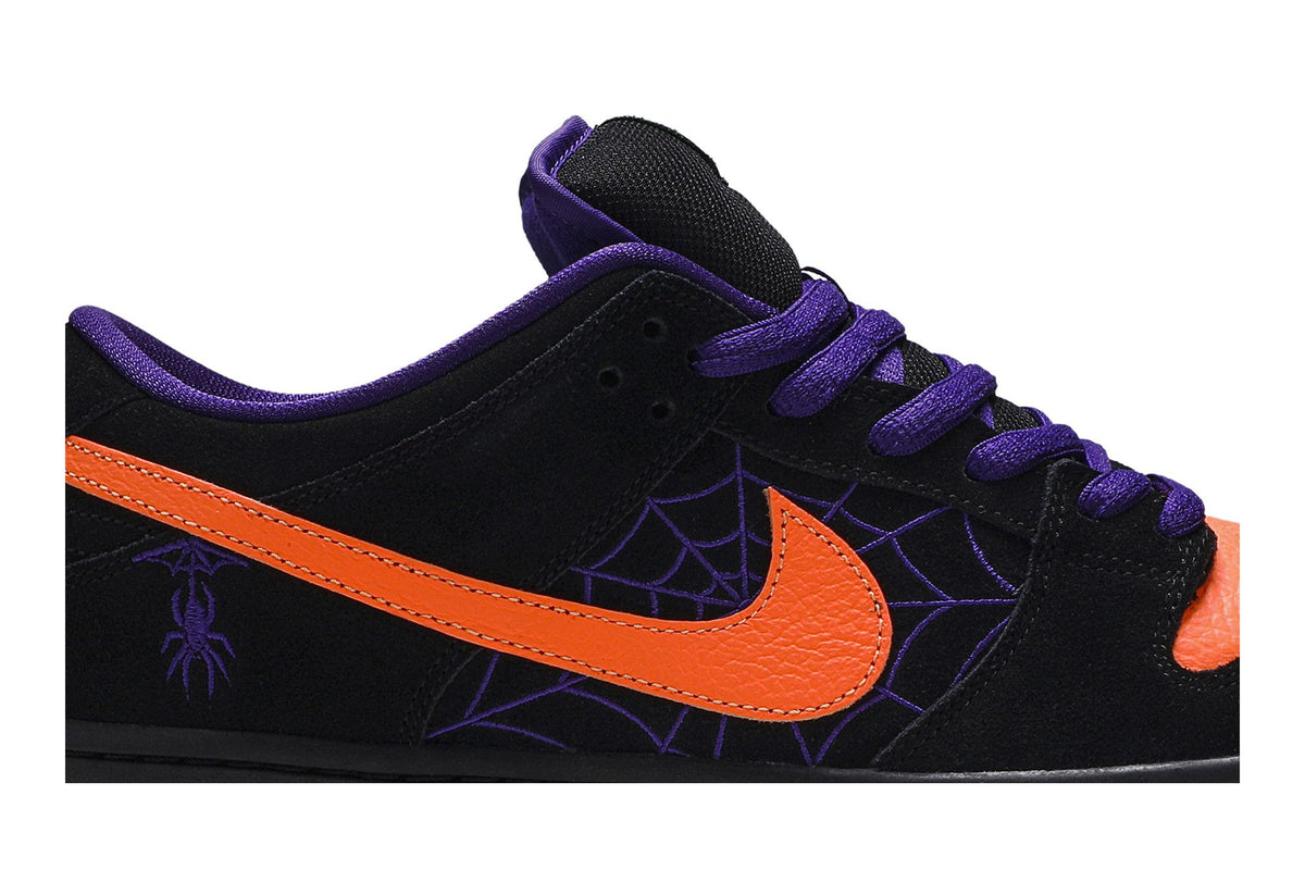 Gros plan de la Nike SB Dunk Low Night of Mischief : daim noir brodé d'une toile d'araignée violette et Swoosh en cuir orange